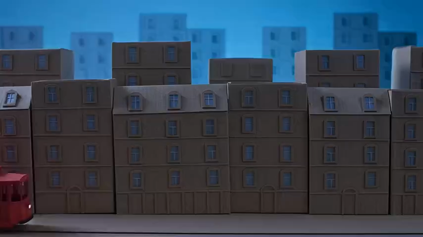 Red paper tram passing layered cardboard buildings at blue hour